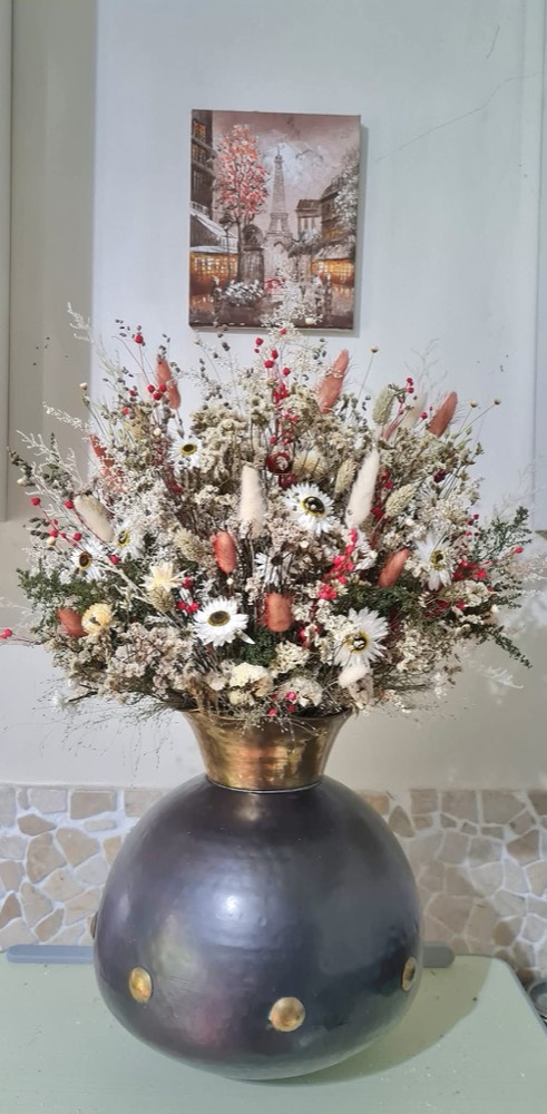 A dried-flower centrepiece in a dark globe vase