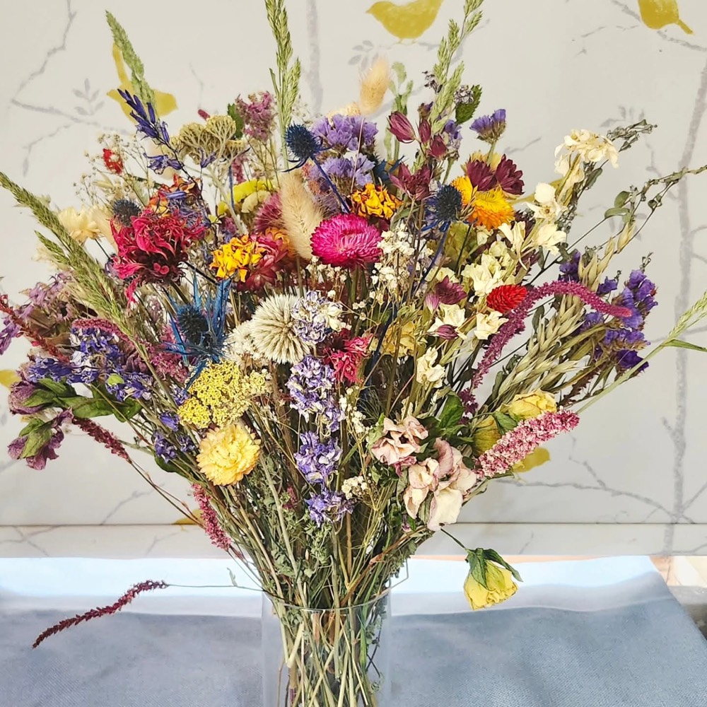 A tall dried-flower arrangement in a glass vase